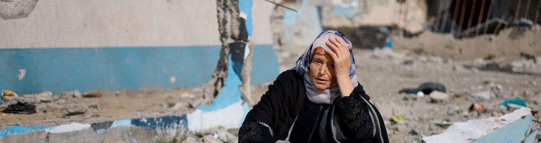 A woman sitting among damaged buildings